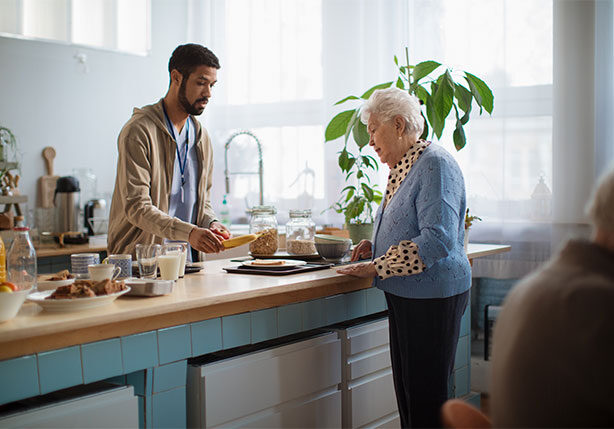 caregiver serving breakfast to elderly woman